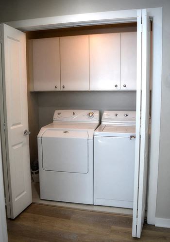 a washer and dryer in a laundry room with white cabinets